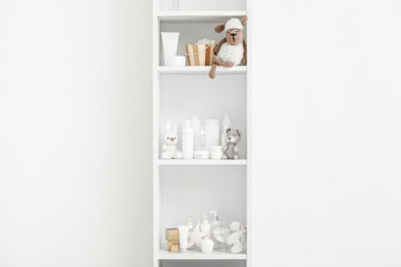 Shelf unit with different bath accessories for children and toys near white wall