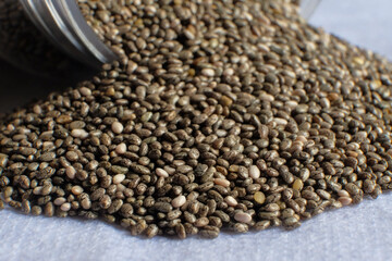 Detail of chia seeds scattered in pile on white background.