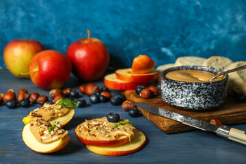 Fresh apple rounds and wedges with nut butter on color wooden table
