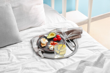 Tray with delicious breakfast in bedroom