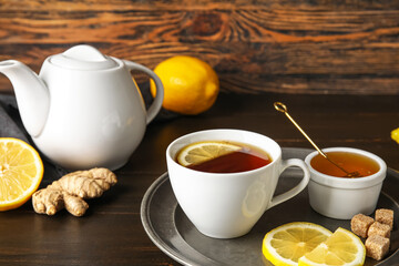 Plate with cup of black tea, lemon, cane sugar and honey on dark wooden background