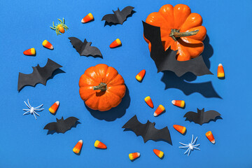 Obraz na płótnie Canvas Paper bats with Halloween pumpkins and candy corns on blue background