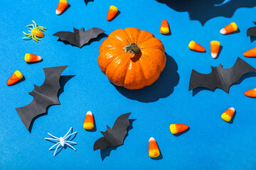 Naklejka na ściany i meble Paper bats with Halloween pumpkin and candy corns on blue background