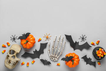 Paper bats with Halloween pumpkins, candy corns and decor on grey background