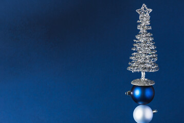 Christmas toys and a Christmas tree made of silver tinsel on a dark blue background. Unusual Christmas tree