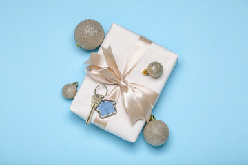 Key from new house with gift and Christmas balls on blue background