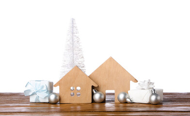 House figures with Christmas tree, balls and gifts on table against white background