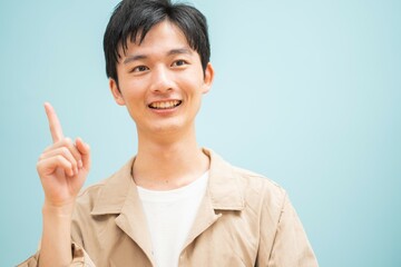 ブルーバックで指さしをするジャケットを着た若い日本人男性