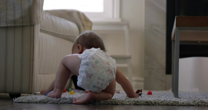 Baby girl playing with toys in living room sits down on diaper - wide shot