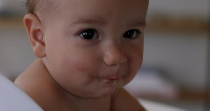 Baby girl being spoon fed in highchair - close up on face