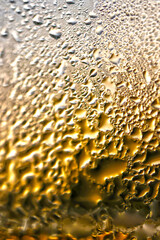 Frost and water droplets reflected on the golden shining glass give the impression of a countless crater-like texture (Retouched and color manipulated image) Based by high macro photography.