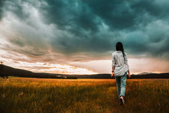 Woman Walking In The Yellow Field Under Sunset 