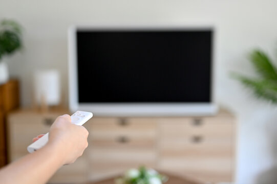 Close-up, A young female using TV remote control to turn on her smart TV