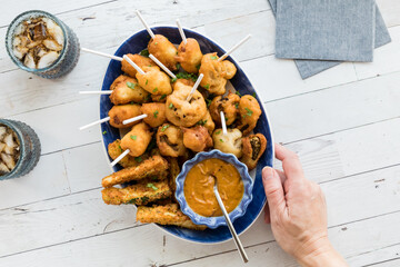 A hand serving a platter of deep fried appetizers, for sharing.