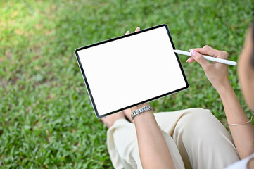 Close-up, Asian female using her tablet while relaxing in the park. tablet white screen mockup
