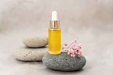 Cosmetology product for facial care. Serum in glass bottle with pipette on stone. Essential oil for care of female skin. Skin care, moisturizing beauty product on pink background.