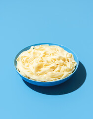 Tagliatelle noodles without sauce in a blue bowl