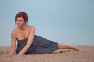 Fototapeta na wymiar adult woman posing on the sand in dress