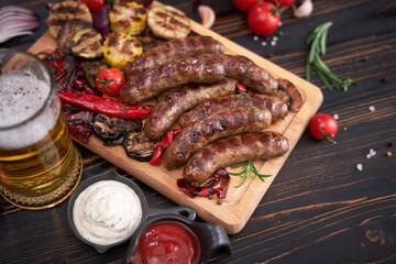 Grilled sausages and vegetables on wooden cutting board at domestic kitchen