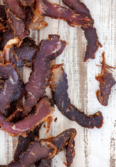 
Sliced traditional South African biltong or cured meat on rustic white wooden surface

