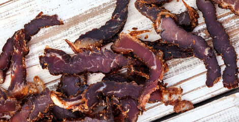 
Sliced traditional South African biltong or cured meat on rustic white wooden surface
