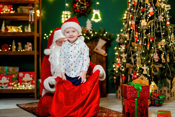 Happy little cute boy having fun with Santa Clause while planning with a sack. New Year concept. 