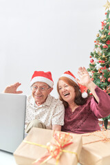 Fototapeta na wymiar Mature Hispanic couple greeting their loved ones via video call during Christmas using a laptop. Concepts: the joy of sharing during the holidays, the use of technology and social media to communicate