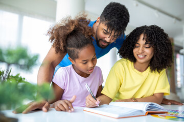 Multiethnic parents helping daughter with her homework at home. Young father and mother helping daughter study at living room. Little girl completing her exercises with the help of dad and mom.