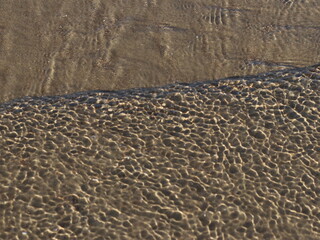 A transparent sea wave running over the sand