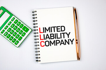 LLC - Limited liability company text on notepad next to calculator and pen.