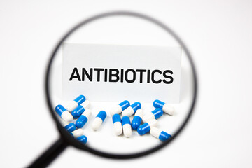 Antibiotics - text next to capsules and medical drugs.