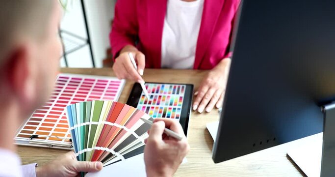 Woman working with color palette and tablet in office discussing color choice with client.