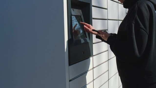 Unrecognizable woman Collecting parcel from shopping locker. Woman Skans QR Code on Mobile phone Self-service Locker Cell with Bar code Reader Modern Shipping and Delivery Concept with Contactless