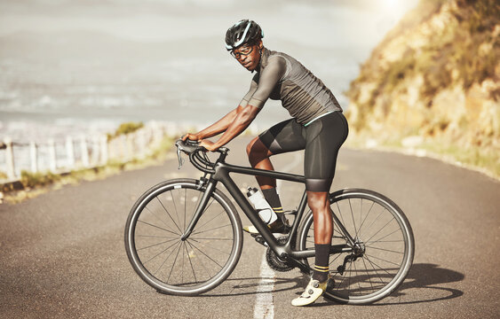 Cycling, energy and bike cyclist in a road along a mountain, power, focus and mindset in South Africa. Sports, fitness and marathon training with black man riding along views of the city on a bicycle