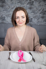 Portrait of a beautiful middle-aged brunette woman sitting at a table with cutlery, a concept on the theme of proper nutrition and women's health