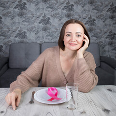 Portrait of a beautiful middle-aged brunette woman sitting at a table with cutlery, a concept on the theme of proper nutrition and women's health