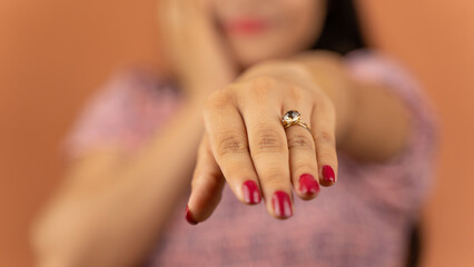 Beautiful excited young Indian woman wearing dress standing isolated over color background, engagement ring on her finger