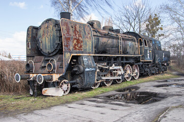 Fototapeta na wymiar An old and dilapidated historic PKP steam locomotive standing on a siding on a gloomy autumn day. Rail.