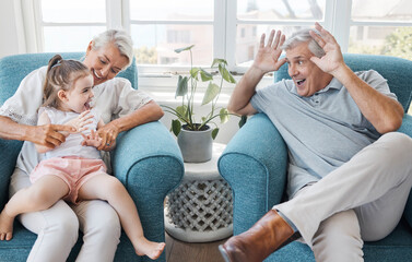 Happy, grandfather and grandmother with child, excited and bonding being silly, goofy or funny in living room at home. Elderly man, senior woman or grandchild being playful, connect or laugh together