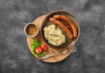 Grilled Beef bratwurst with mash potato on modern plate on wooden board.  BBQ beef sausages. German sausages. Rinderbratwurst