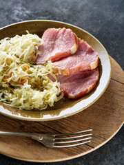 Backed Kasseler pork steak with sauerkraut. Smoked pork lion. Sliced smoked pork chop on wooden board