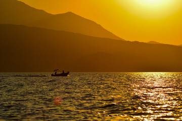Silhouette of boat in the lake at sunset. Fisherman rowing in the lake. Rowing at sunset in Beyşehir lake. 