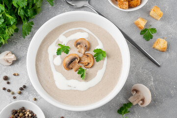 Mushroom cream soup with cream, croutons and herbs on a white wooden background. Delicious comfort food.
