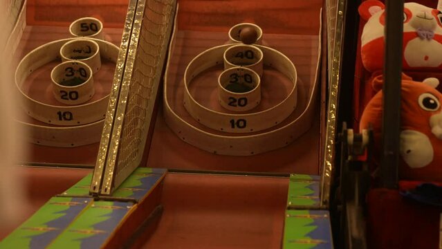 Person rolls a skee-ball down the lane at an arcade.