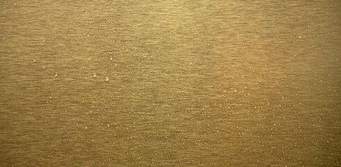 Photo of a golden background in small raindrops. Golden rectangular background for text. Dew drops...