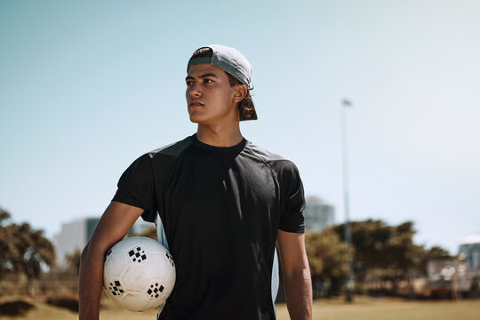 Soccer, sports and training with a man athlete holding a ball on a grass pitch or field before a game. Fitness, football and exercise with a male player thinking about a match outside during summer