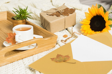 Autumn mockup with letter in golden envelope, tea, sunflowers and gift 
