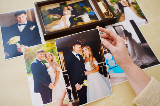 printed wedding photos in the hands and in a wooden box with a flash drive. 