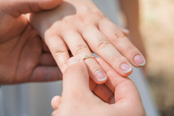 Obraz na płótnie Canvas A man puts a wedding ring on a woman's finger, Close-up.