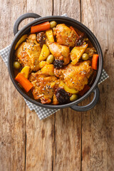 Gallo en chicha Salvadoran chicken braised in fizzy and tangy pineapple chicha with vegetables closeup on the pan on the wooden table. Vertical top view from above